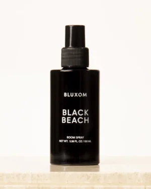 bluxom black beach room and linen spray in a black minimalist bottle with sea salt, sage, and soft wood coastal fragrance.