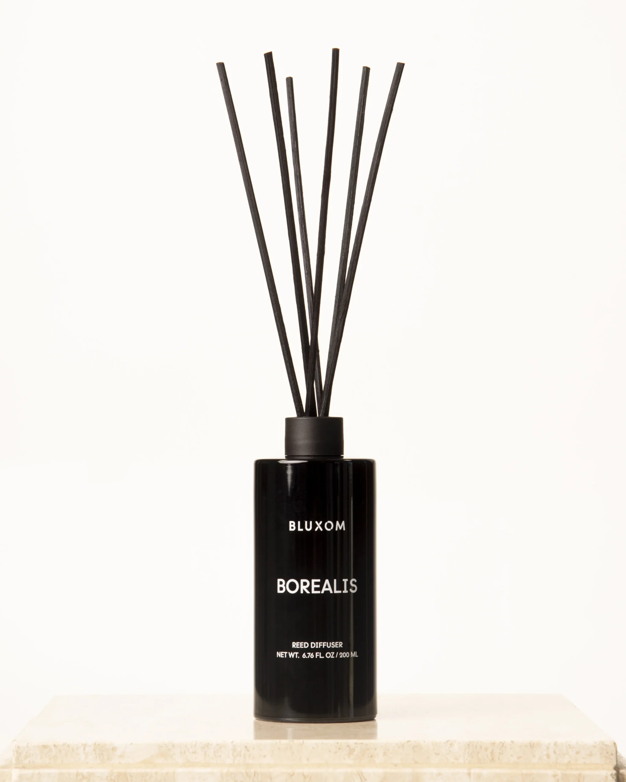 BLUXOM Borealis reed diffuser in a sleek black glass bottle with natural reeds and winter eucalyptus–fir fragrance